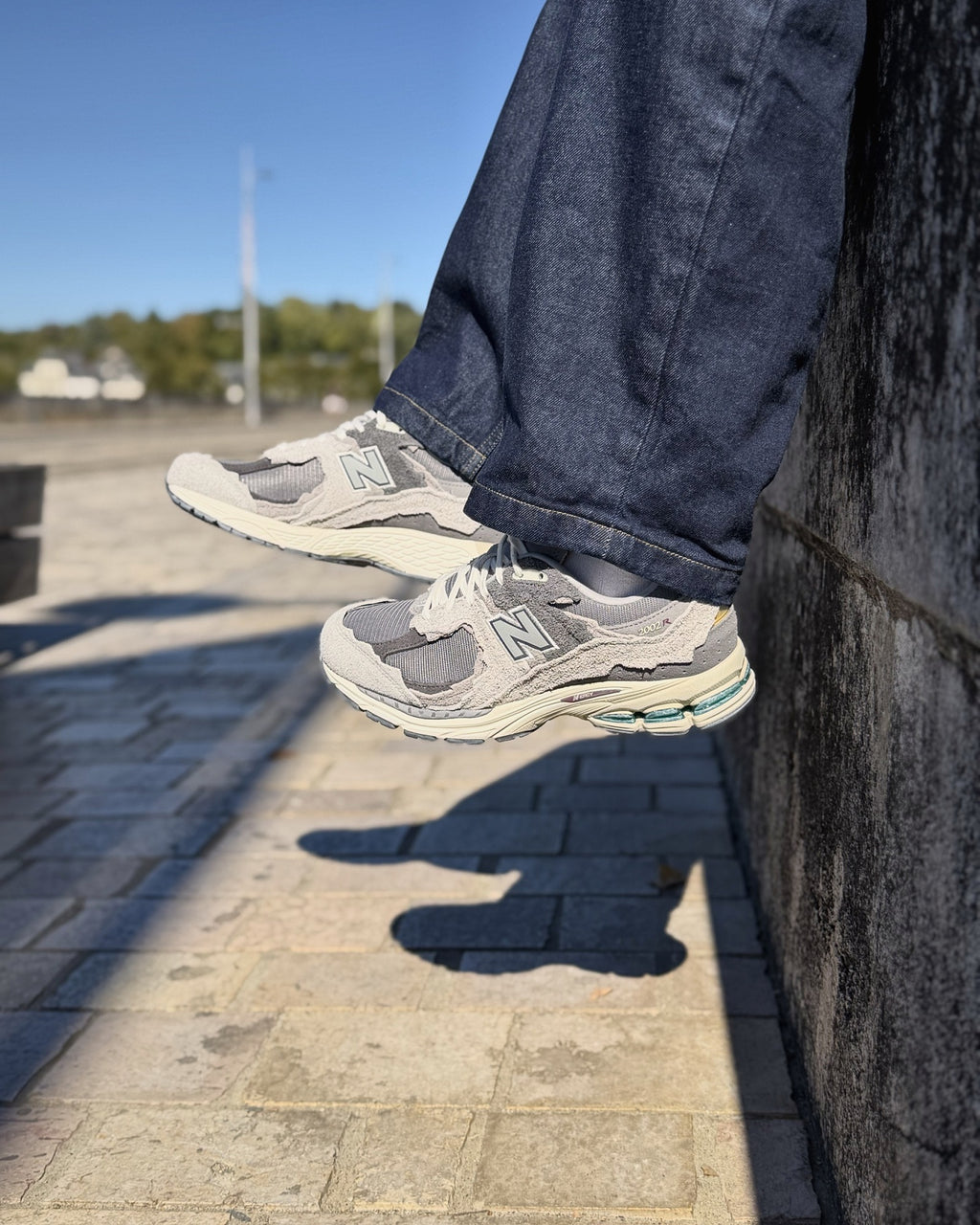 New Balance 2002R Protection Pack Rain Cloud portée contre un mur
