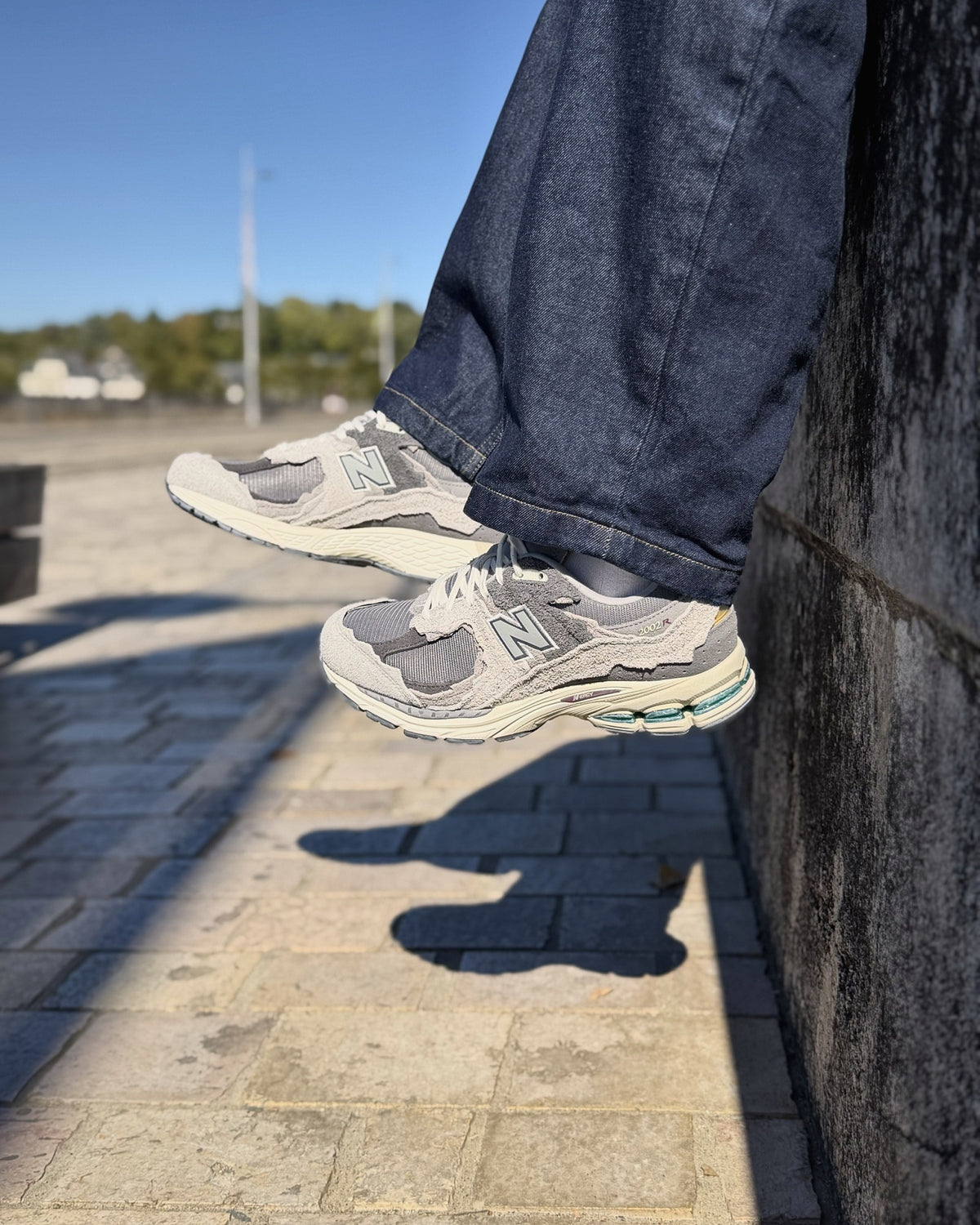 New Balance 2002R Protection Pack Rain Cloud portée contre un mur