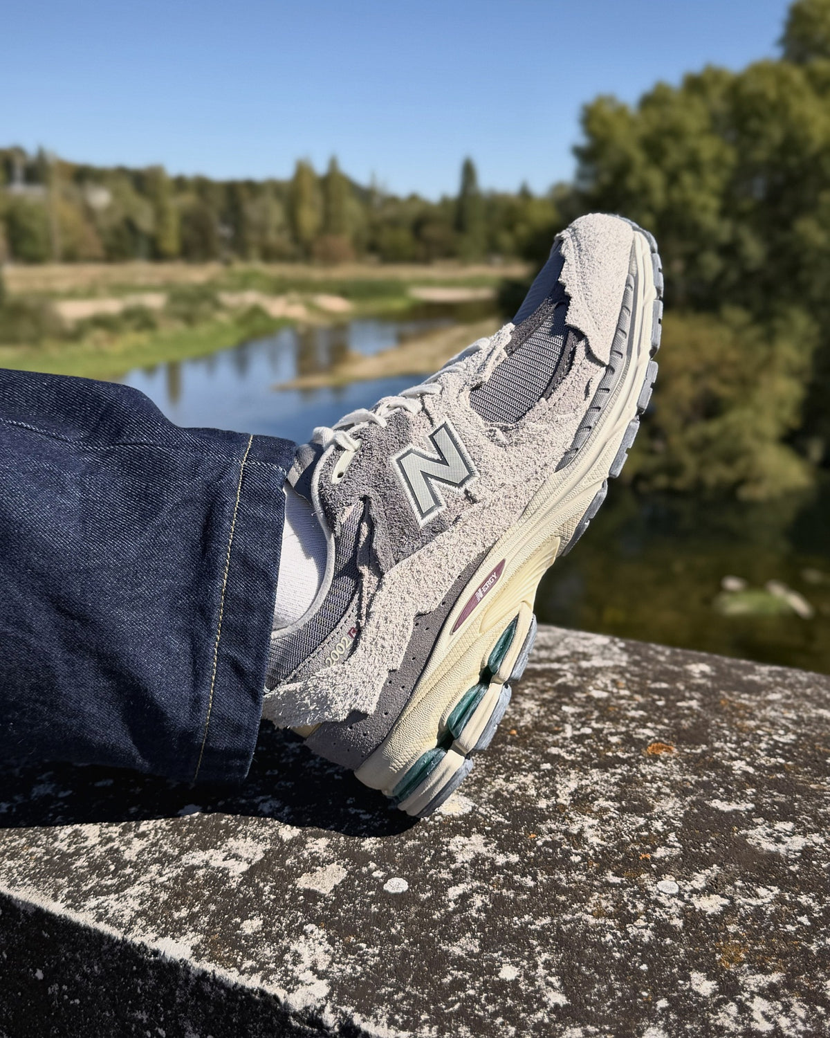 New Balance 2002R Protection Pack Rain Cloud sur un parapet au bord de la Loire