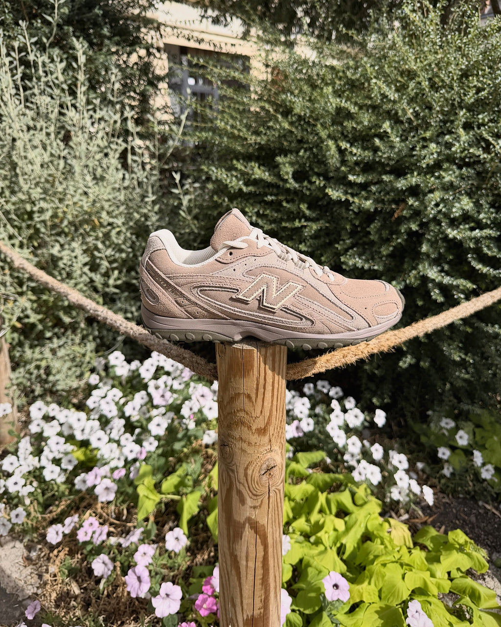 New Balance 204L Mushroom Arid Stone vue de profil dans un jardin