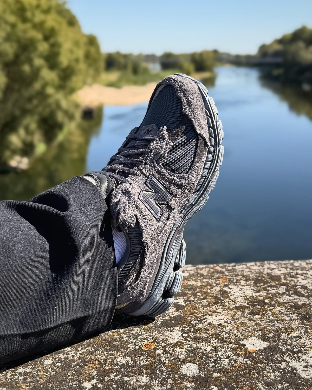 New Balance 2002R Protection Pack Phantom sur un parapet au bord de la Loire