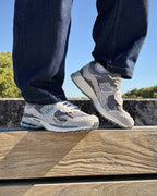 New Balance 2002R Protection Pack Rain Cloud portées en duo sur un banc