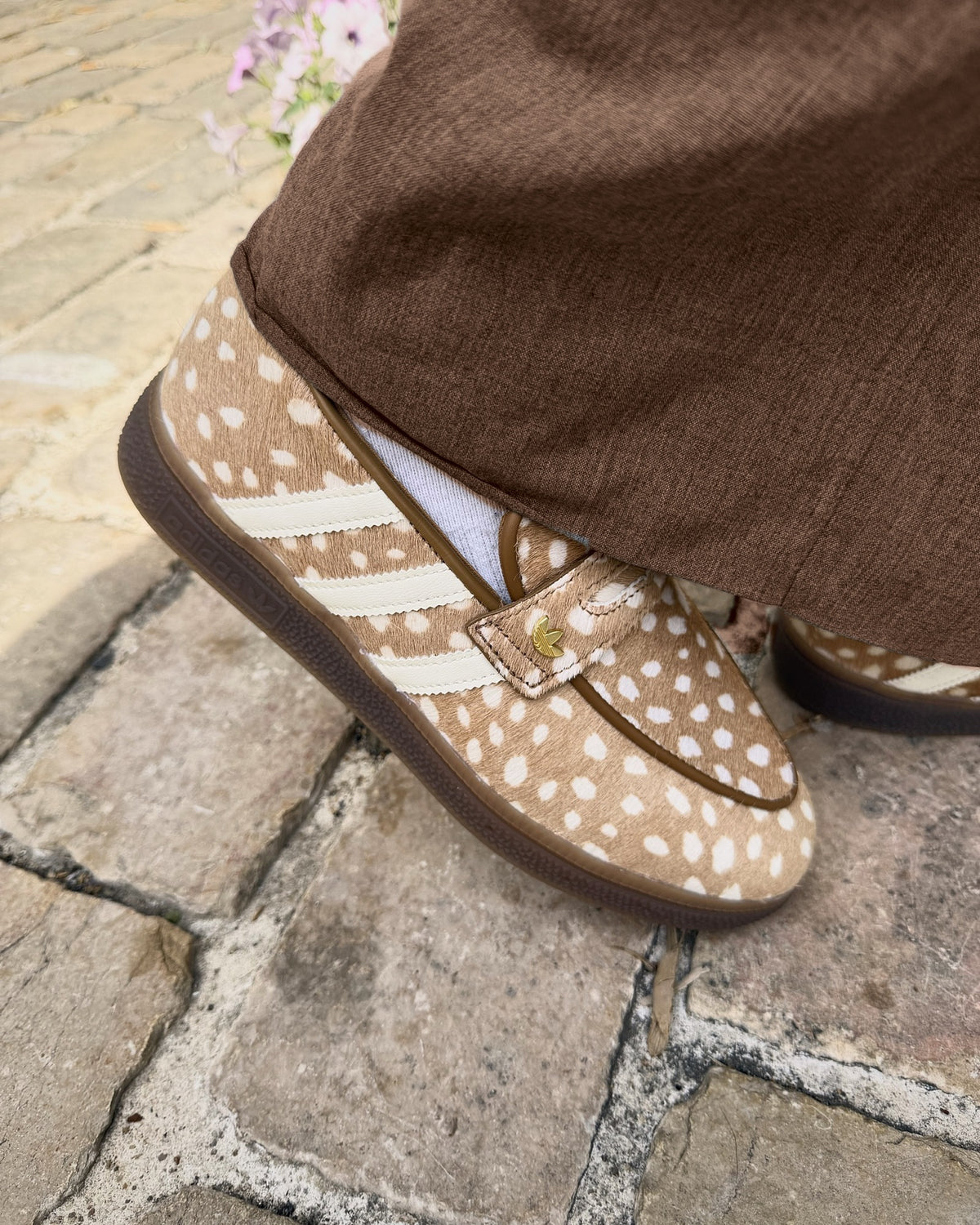 Détail du trèfle doré de la adidas Handball Spezial Loafer Bambi, portée avec un pantalon chocolat